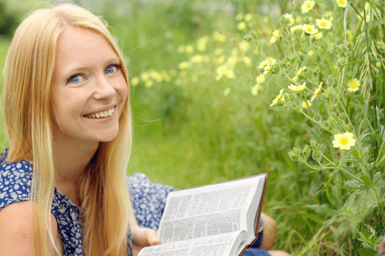 happy woman reading Bible in a field