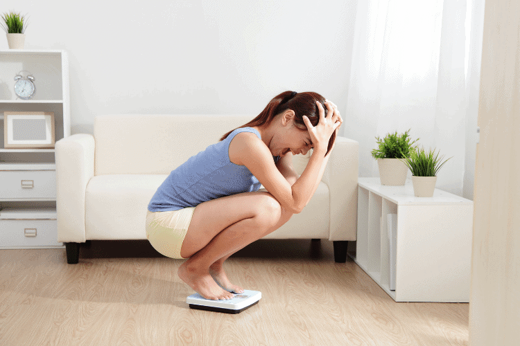 woman on scale frustrated by weight loss