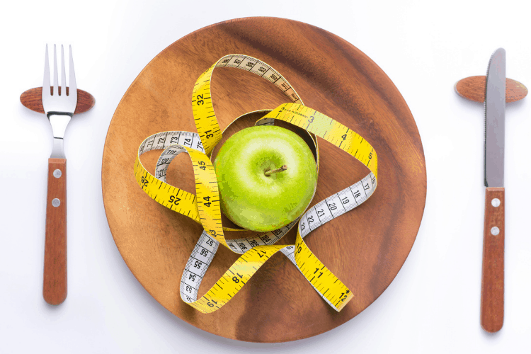 plate with apple, measuring tape, knife and fork