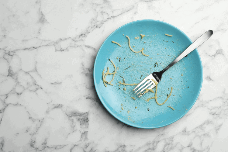 mostly empty plate of pasta with fork