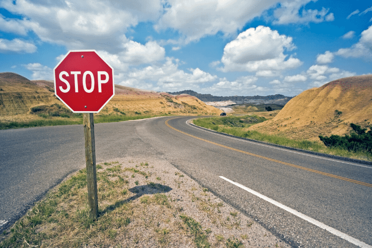 photo of a stop sign at a crossroads with blue sky and sand dunes