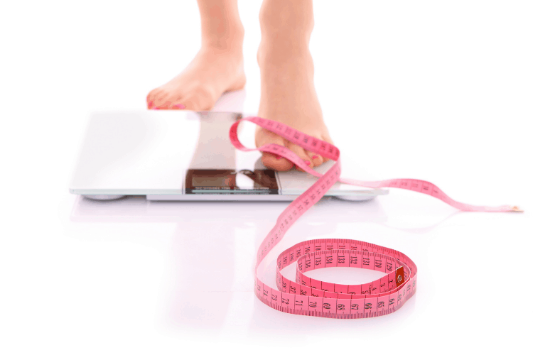 woman's foot on a scale with a measuring tape